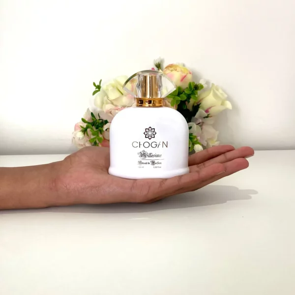 Une main présente le flacon du parfum