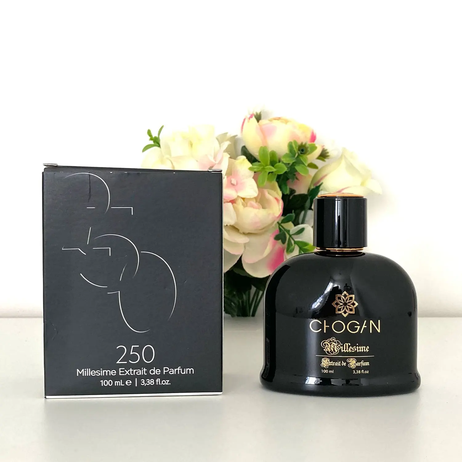 Parfum homme 250 Olfazeta Millesime, flacon noir de 100 ml avec boîte noire assortie, présenté devant un bouquet de fleurs roses et blanches