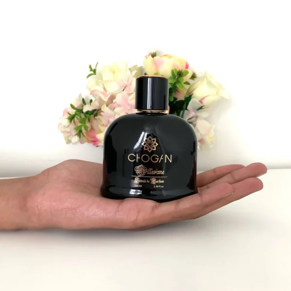 Parfum Chogan Millésime en flacon noir élégant, tenu dans une main avec un fond floral