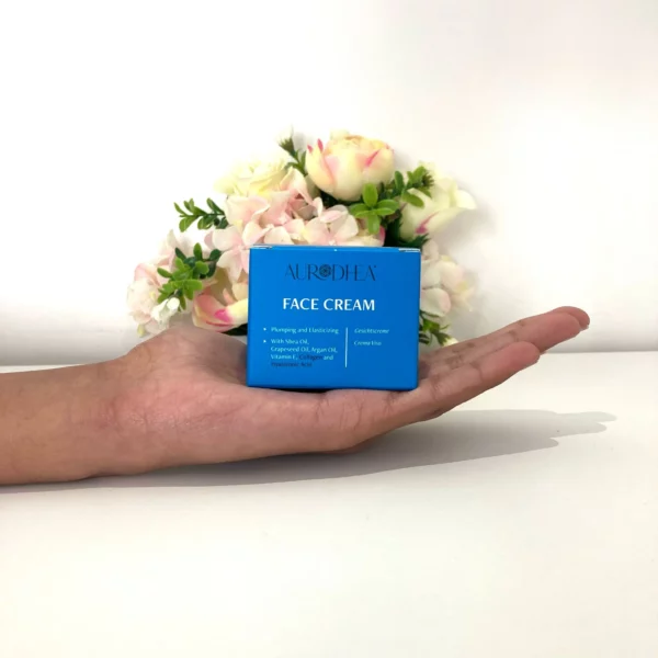 Crème visage Aurodhea repulpante et raffermissante – boîte bleue tenue dans une main pour illustration de la taille, avec huile de karité, huile de pépins de raisin, huile d’argan, collagène, vitamine E et acide hyaluronique